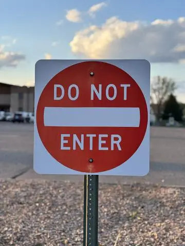 Red circular DO NOT ENTER sign with a white horizontal bar at a parking lot exit