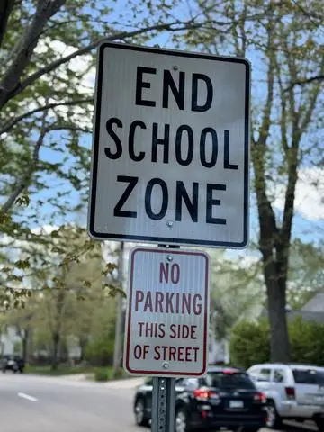 White sign reading END SCHOOL ZONE above a no-parking plaque