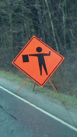 Orange diamond construction sign showing a worker holding a flag