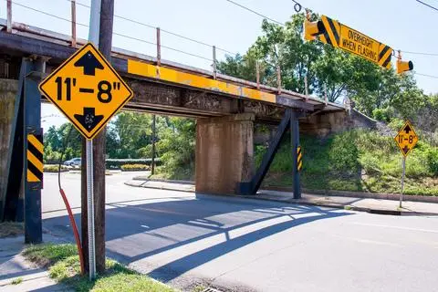 Yellow diamond low clearance sign reading 11 feet 8 inches in front of a railway bridge