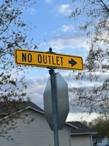 Yellow street-mounted plaque reading NO OUTLET with an arrow