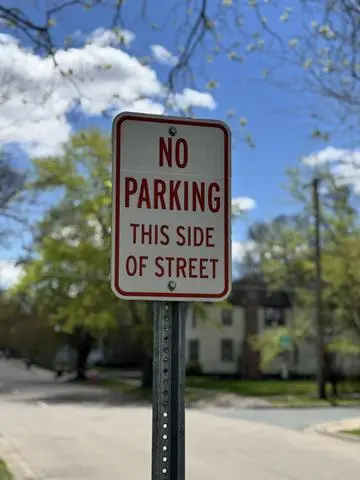 Red and white sign reading NO PARKING THIS SIDE OF STREET