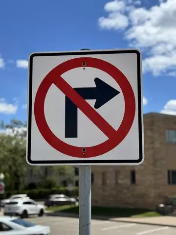 White sign showing a right-turn arrow crossed by a red circle and slash