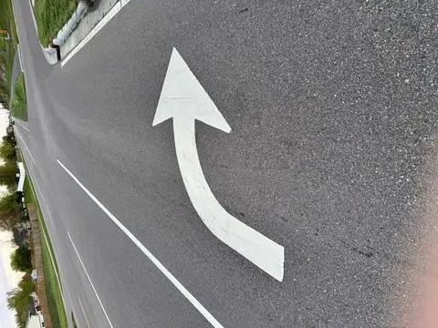 A white curved arrow painted on the road surface indicating a required right turn
