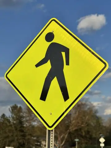 Yellow diamond sign showing a walking pedestrian symbol