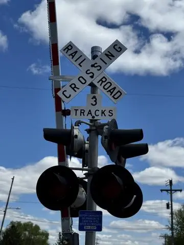 Railroad crossing with lowered-style gates, signals and a crossbuck marked 3 TRACKS