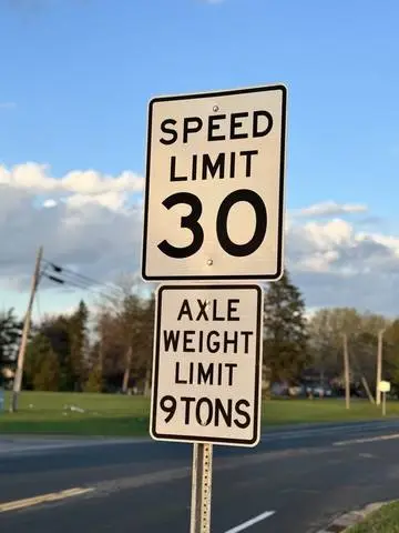 SPEED LIMIT 30 sign above a plaque reading AXLE WEIGHT LIMIT 9 TONS