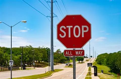 Red STOP sign with an ALL WAY plaque at a wide suburban intersection