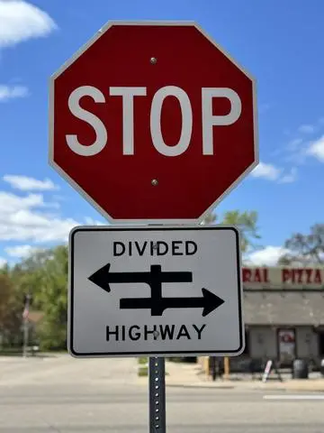 Red STOP sign above a plaque showing a DIVIDED HIGHWAY symbol
