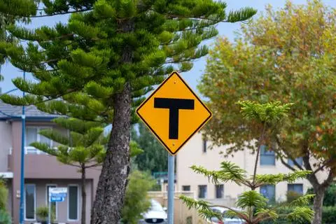 Yellow diamond sign showing a black T shape for a T intersection ahead